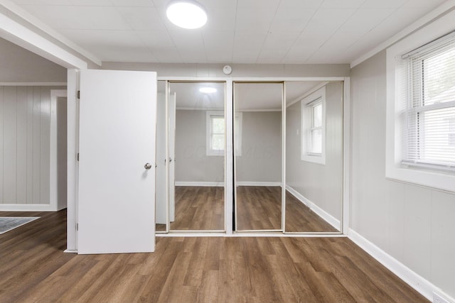 unfurnished bedroom with wood finished floors, baseboards, and multiple closets