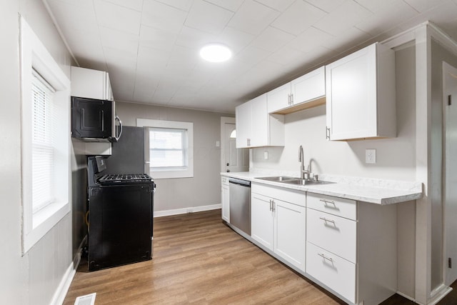 kitchen with a sink, appliances with stainless steel finishes, light wood-style floors, and white cabinets