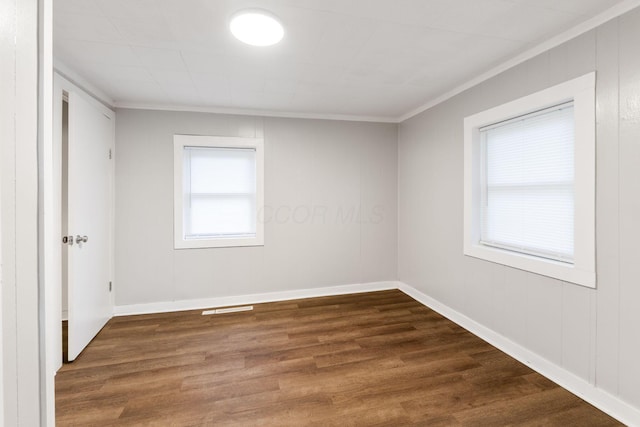 spare room featuring crown molding, dark wood-style floors, and baseboards