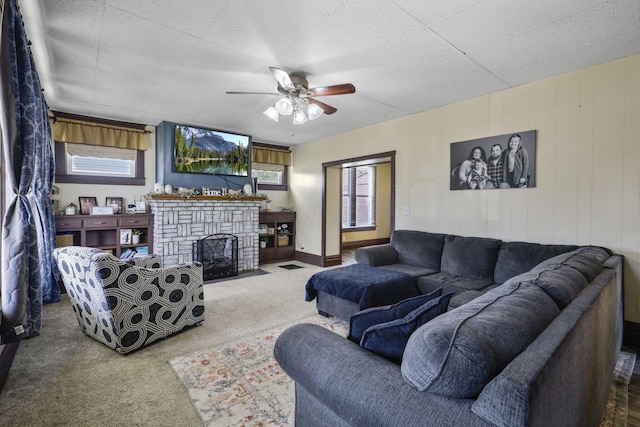 carpeted living area featuring ceiling fan and a fireplace