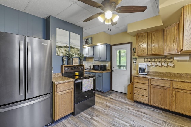 kitchen with a ceiling fan, brown cabinets, light countertops, stainless steel appliances, and light wood-style flooring