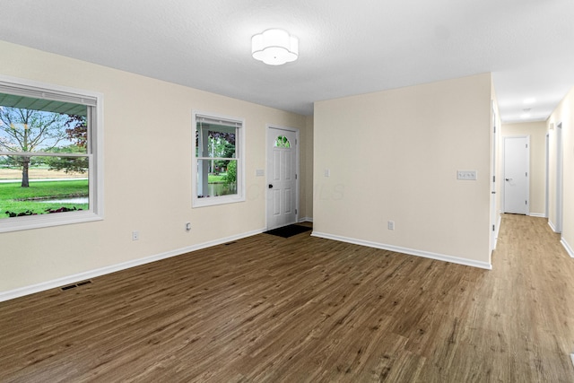 spare room featuring baseboards, visible vents, a wealth of natural light, and wood finished floors