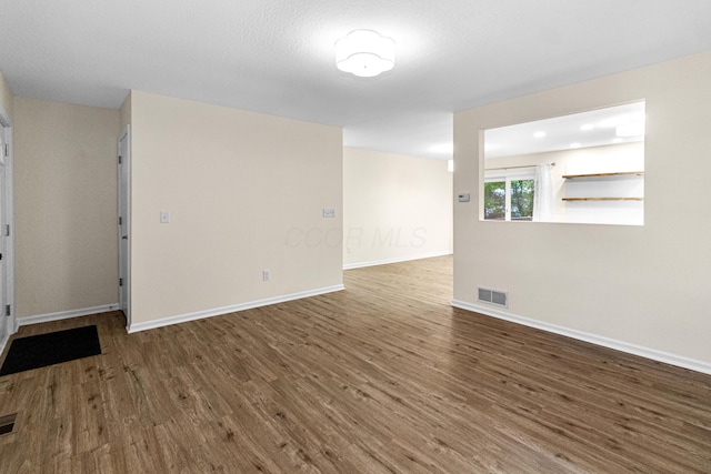 empty room featuring visible vents, baseboards, and wood finished floors