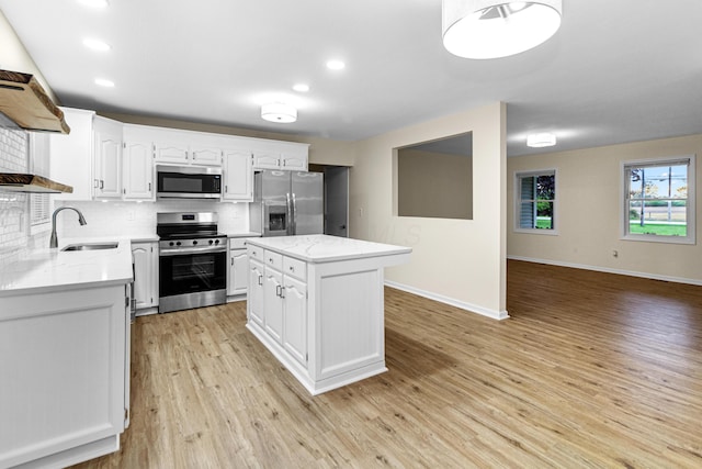 kitchen featuring decorative backsplash, light wood-type flooring, white cabinets, a sink, and appliances with stainless steel finishes