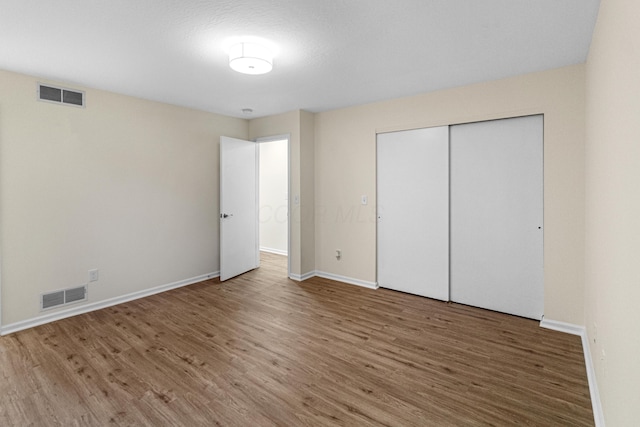 unfurnished bedroom with baseboards, visible vents, and wood finished floors