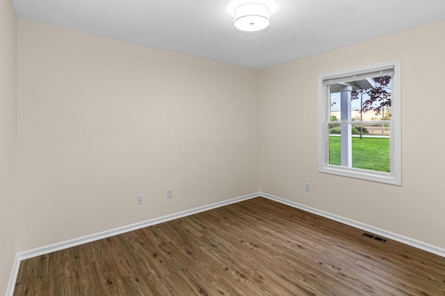 empty room featuring baseboards, wood finished floors, and visible vents
