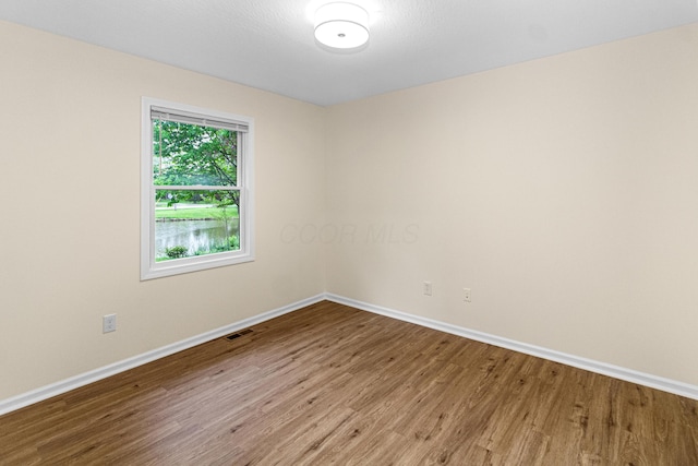 unfurnished room featuring baseboards, wood finished floors, and visible vents