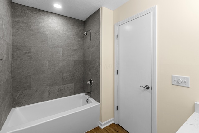 bathroom with recessed lighting, wood finished floors, and shower / washtub combination