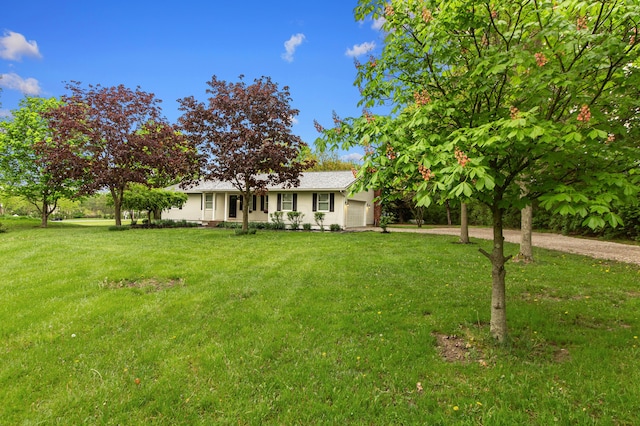 ranch-style home featuring dirt driveway, an attached garage, and a front lawn