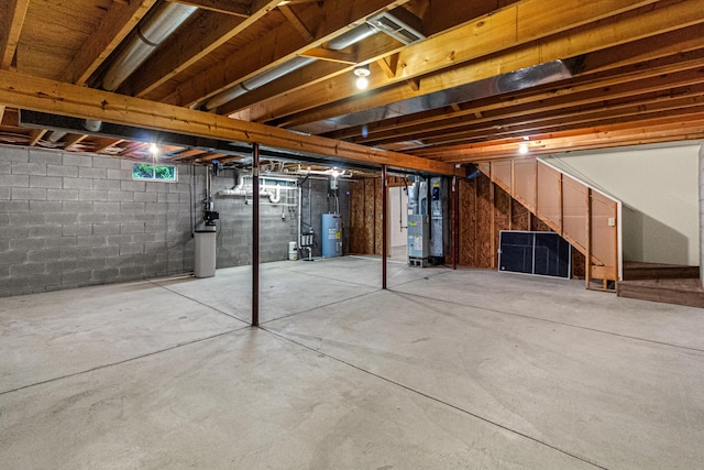 unfinished below grade area featuring stairs, water heater, gas water heater, and concrete block wall