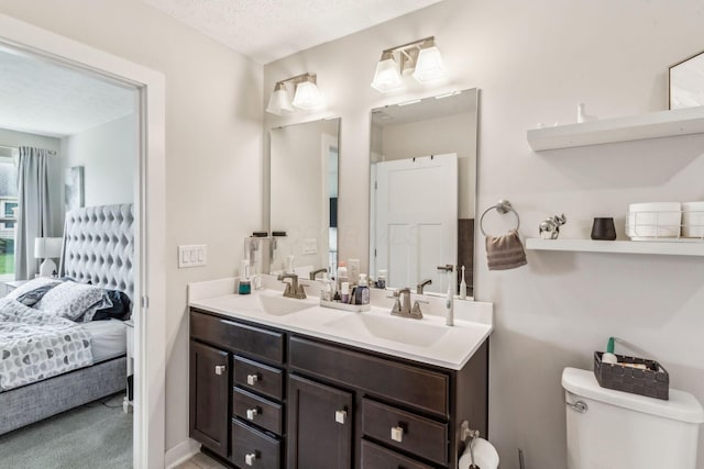 bathroom with ensuite bathroom, a sink, double vanity, and toilet