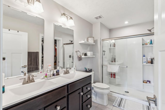 full bathroom featuring double vanity, a sink, tile patterned floors, and a shower stall