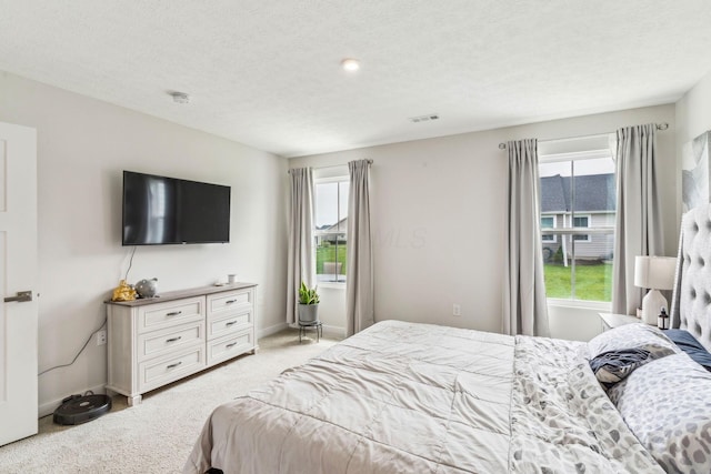 bedroom featuring baseboards, visible vents, multiple windows, and light carpet
