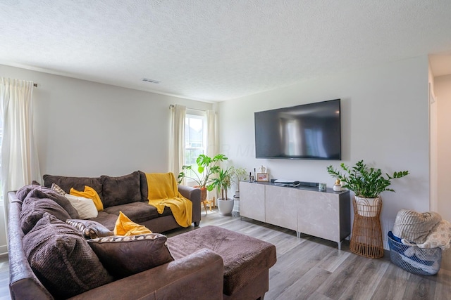 living room with a textured ceiling, visible vents, and wood finished floors