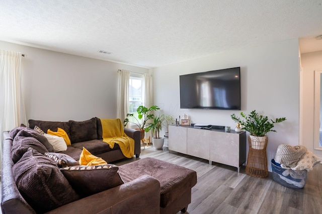 living area featuring a textured ceiling, wood finished floors, and visible vents