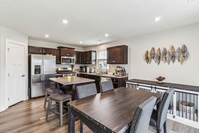kitchen featuring light wood-style flooring, a kitchen island, dark brown cabinets, and stainless steel appliances
