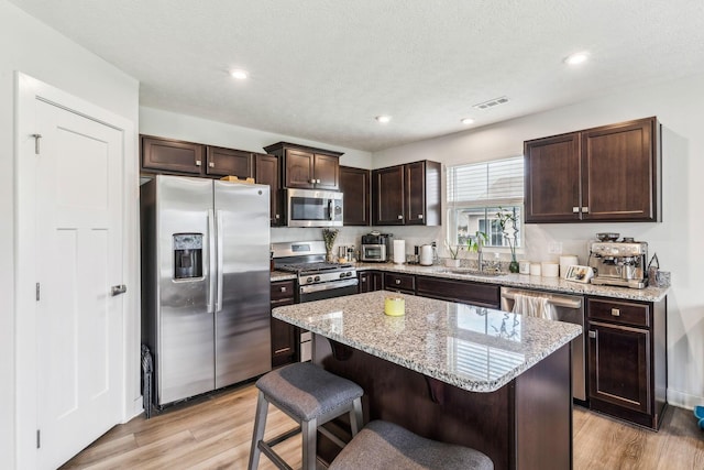 kitchen with a sink, stainless steel appliances, light wood-type flooring, and visible vents