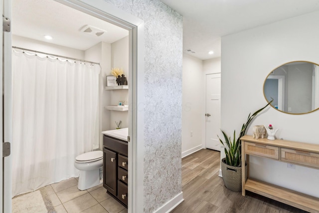 bathroom featuring a shower with curtain, visible vents, wood finished floors, vanity, and toilet