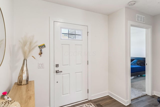 foyer with baseboards, visible vents, and dark wood-style floors