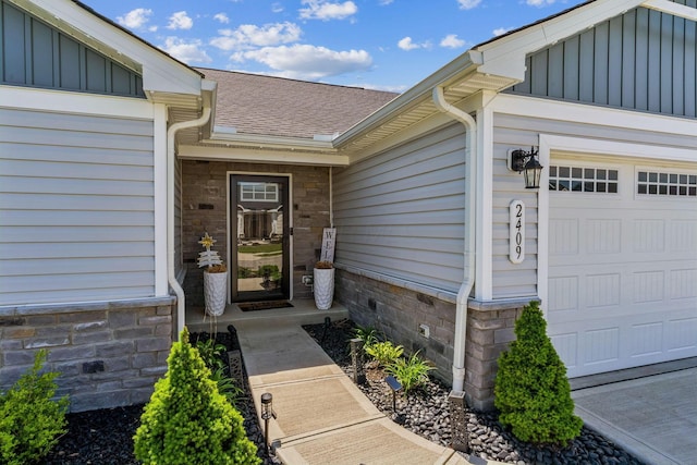 entrance to property featuring roof with shingles, board and batten siding, and an attached garage