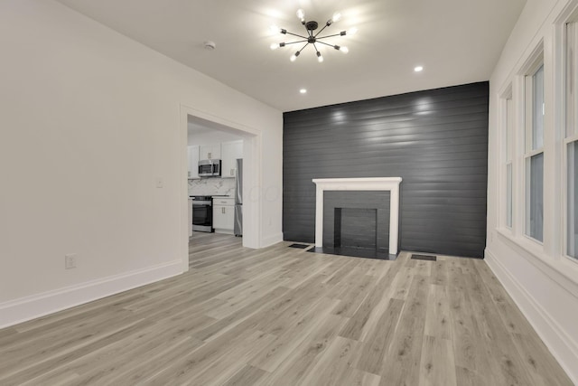 unfurnished living room featuring light wood-style floors, baseboards, a brick fireplace, and a chandelier