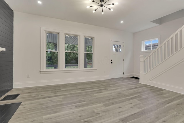 unfurnished living room with a chandelier, stairs, recessed lighting, baseboards, and light wood-type flooring
