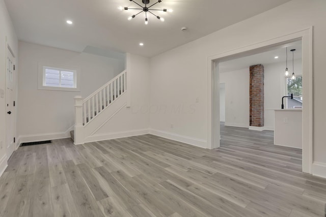 unfurnished living room featuring baseboards, stairway, recessed lighting, a chandelier, and light wood-style flooring