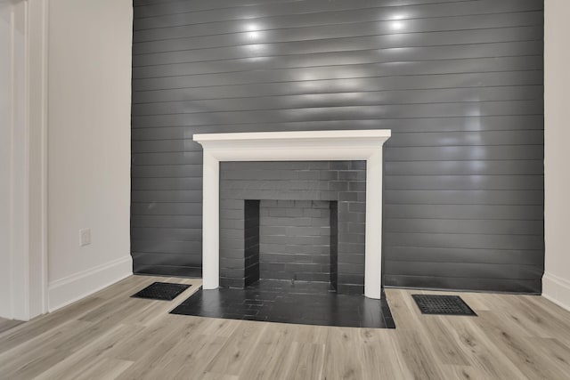 room details featuring baseboards, visible vents, a fireplace with flush hearth, and wood finished floors