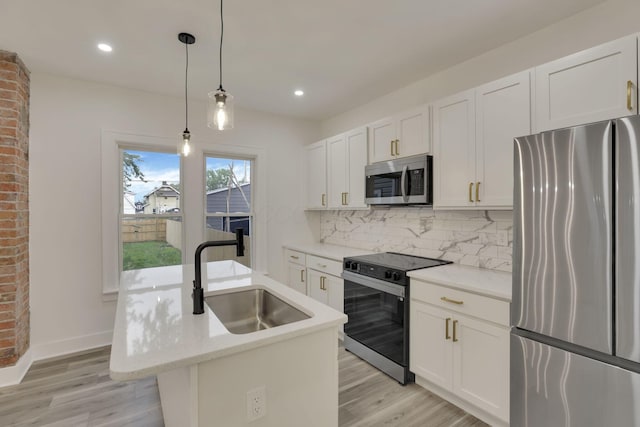 kitchen featuring appliances with stainless steel finishes, a sink, an island with sink, white cabinetry, and decorative backsplash