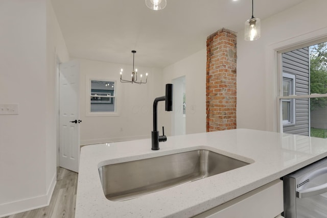 kitchen with decorative light fixtures, light stone counters, a sink, and light wood-style floors