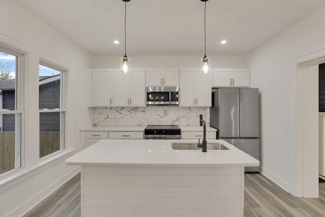 kitchen with a sink, appliances with stainless steel finishes, white cabinets, and tasteful backsplash