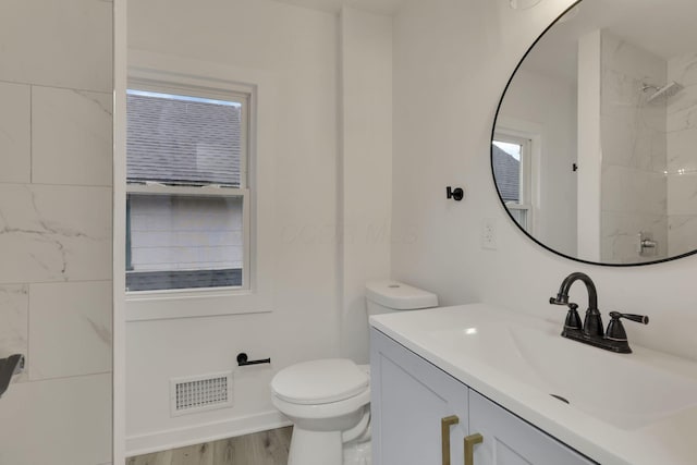 bathroom with visible vents, walk in shower, wood finished floors, vanity, and toilet