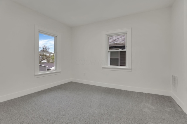 spare room featuring baseboards, visible vents, and dark colored carpet