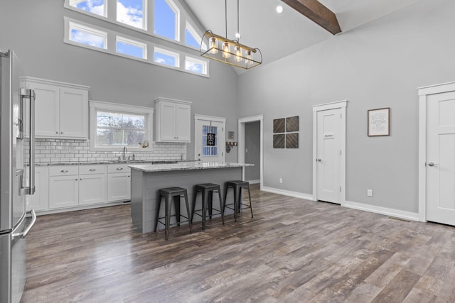 10695 State Route 93 N, Logan, OH 43138 - kitchen with white cabinets, high end fridge, a sink, high vaulted ceiling, and a kitchen island