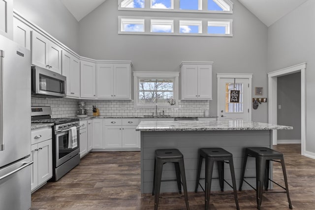 10695 State Route 93 N, Logan, OH 43138 - kitchen featuring white cabinets, appliances with stainless steel finishes, a breakfast bar, high vaulted ceiling, and tasteful backsplash