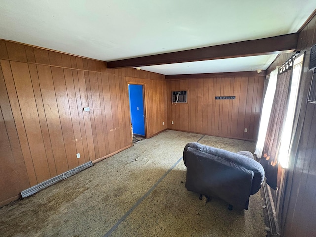 living area featuring beamed ceiling and wood walls