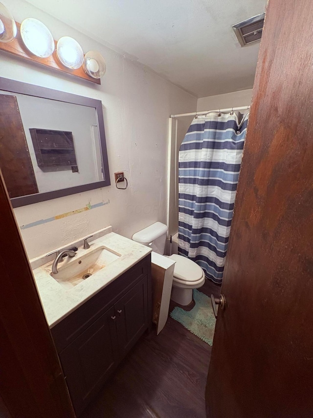 full bathroom featuring vanity, toilet, curtained shower, wood finished floors, and visible vents