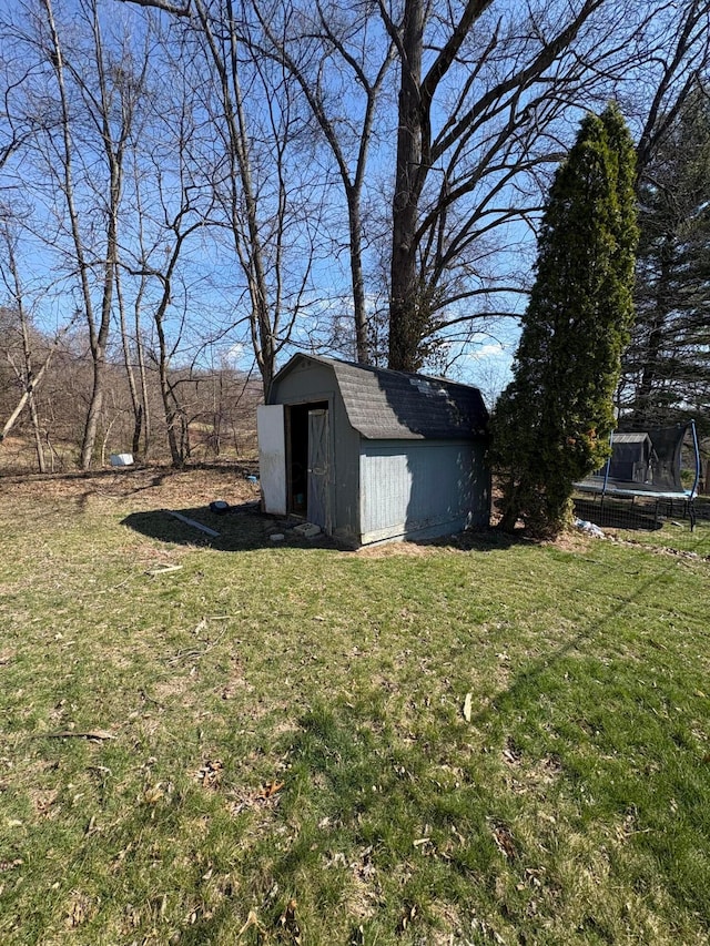 view of yard with a trampoline, an outdoor structure, and a shed