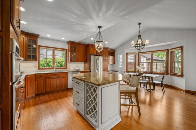 1920 Chatfield Rd, Columbus, OH 43221 - kitchen with stainless steel appliances, brown cabinetry, light wood-style flooring, a breakfast bar area, and lofted ceiling