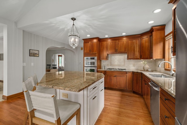 1920 Chatfield Rd, Columbus, OH 43221 - kitchen featuring a sink, arched walkways, stainless steel appliances, light wood-style floors, and light stone counters
