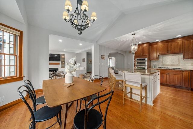1920 Chatfield Rd, Columbus, OH 43221 - dining space featuring a chandelier, arched walkways, lofted ceiling, light wood-style floors, and a fireplace