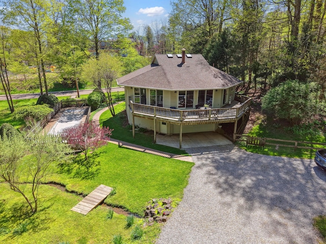 rear view of property featuring a porch, driveway, roof with shingles, a lawn, and fence