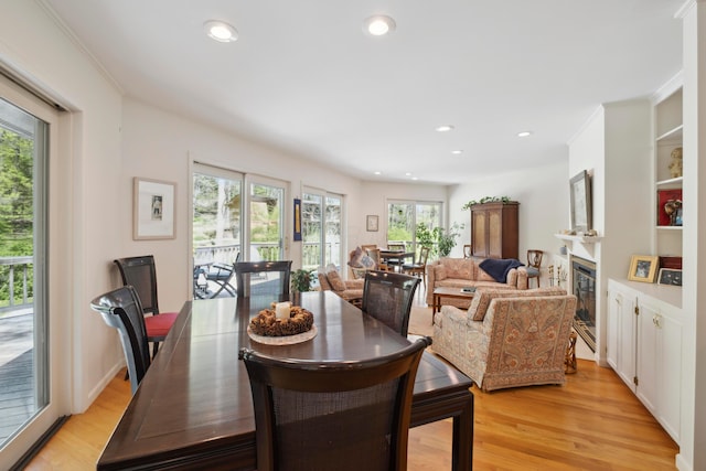 dining area with a glass covered fireplace, recessed lighting, and light wood finished floors