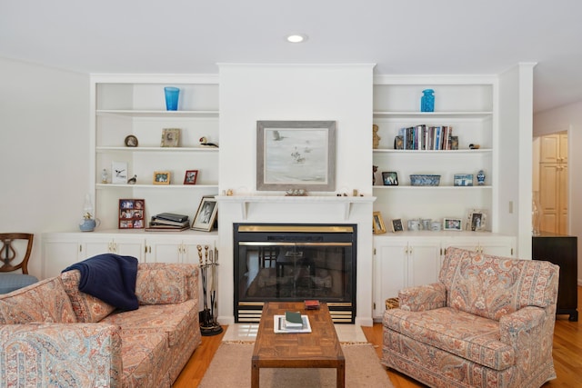living room featuring a glass covered fireplace, recessed lighting, and light wood finished floors