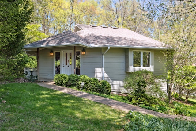 ranch-style house featuring roof with shingles and a front yard