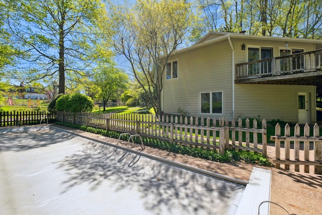 view of side of home with a fenced front yard and a balcony