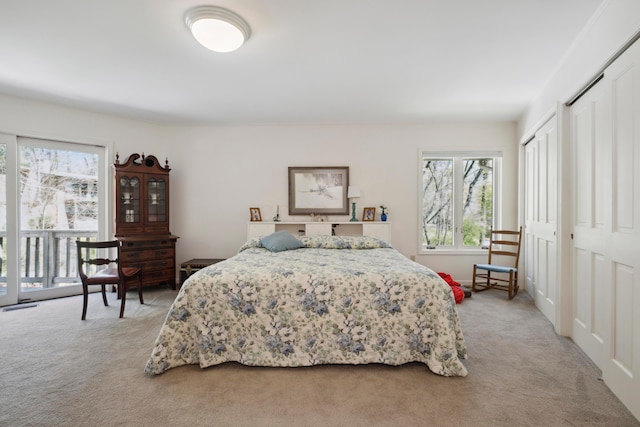 bedroom featuring multiple closets, multiple windows, and light carpet