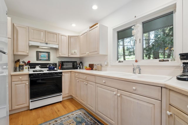 kitchen with black microwave, gas range gas stove, light countertops, under cabinet range hood, and light wood-style flooring