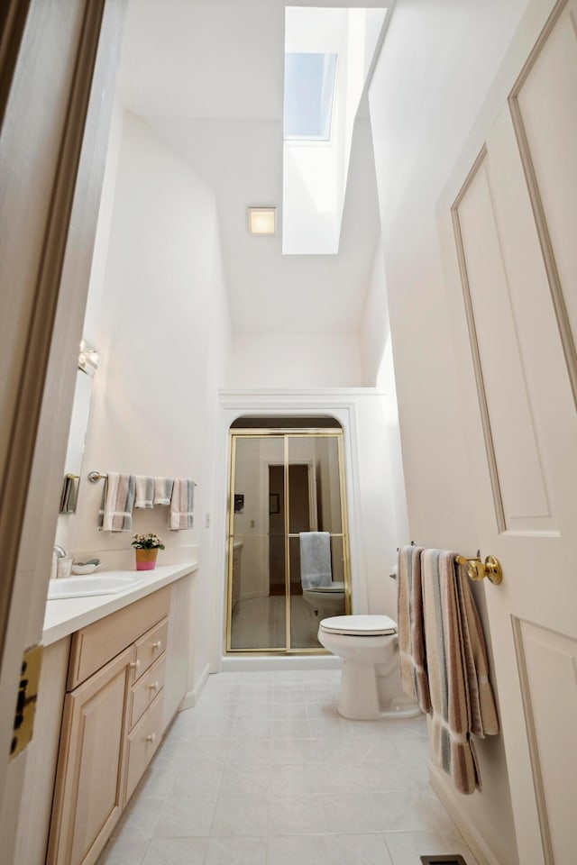 full bath featuring a skylight, vanity, a shower stall, and toilet