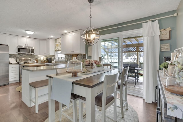 dining area featuring an inviting chandelier, recessed lighting, a textured ceiling, and wood finished floors
